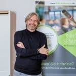 Mann lehnt an Werbetafel mit Mikrofon